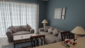 A living room with a sofa, two armchairs, a coffee table, and a TV. There are decorative pillows and a lamp on the sofa. - 
Orlando Dreams Come True – Private Splash Pool, 3 En-Suite BRs, Near Disney (Kissimmee)