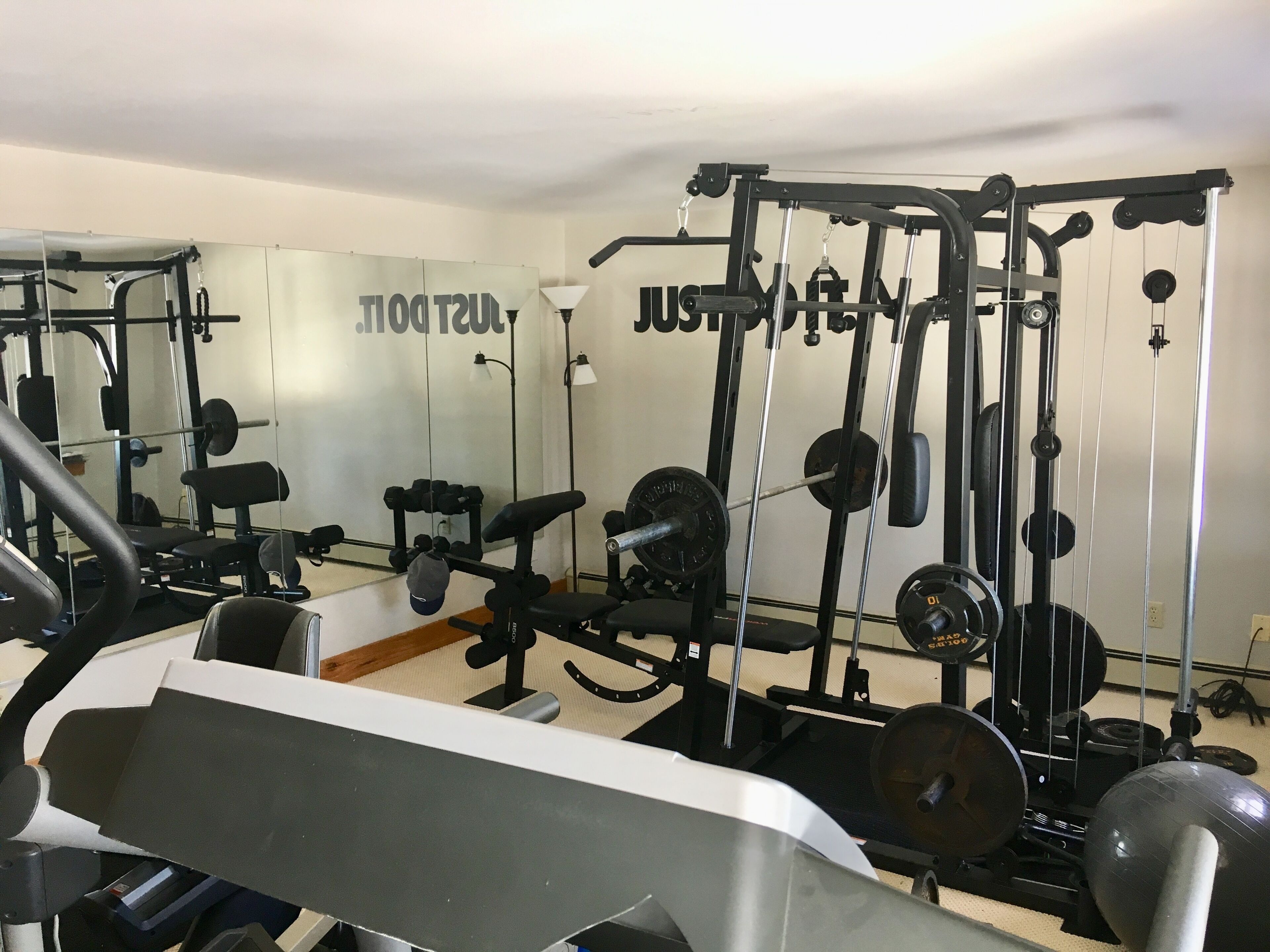 A gym with various exercise equipment, including weight machines, benches, and dumbbells.