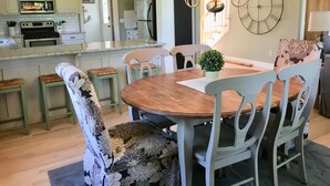 Un comedor con mesa y sillas de madera, un candelabro y un reloj en la pared.