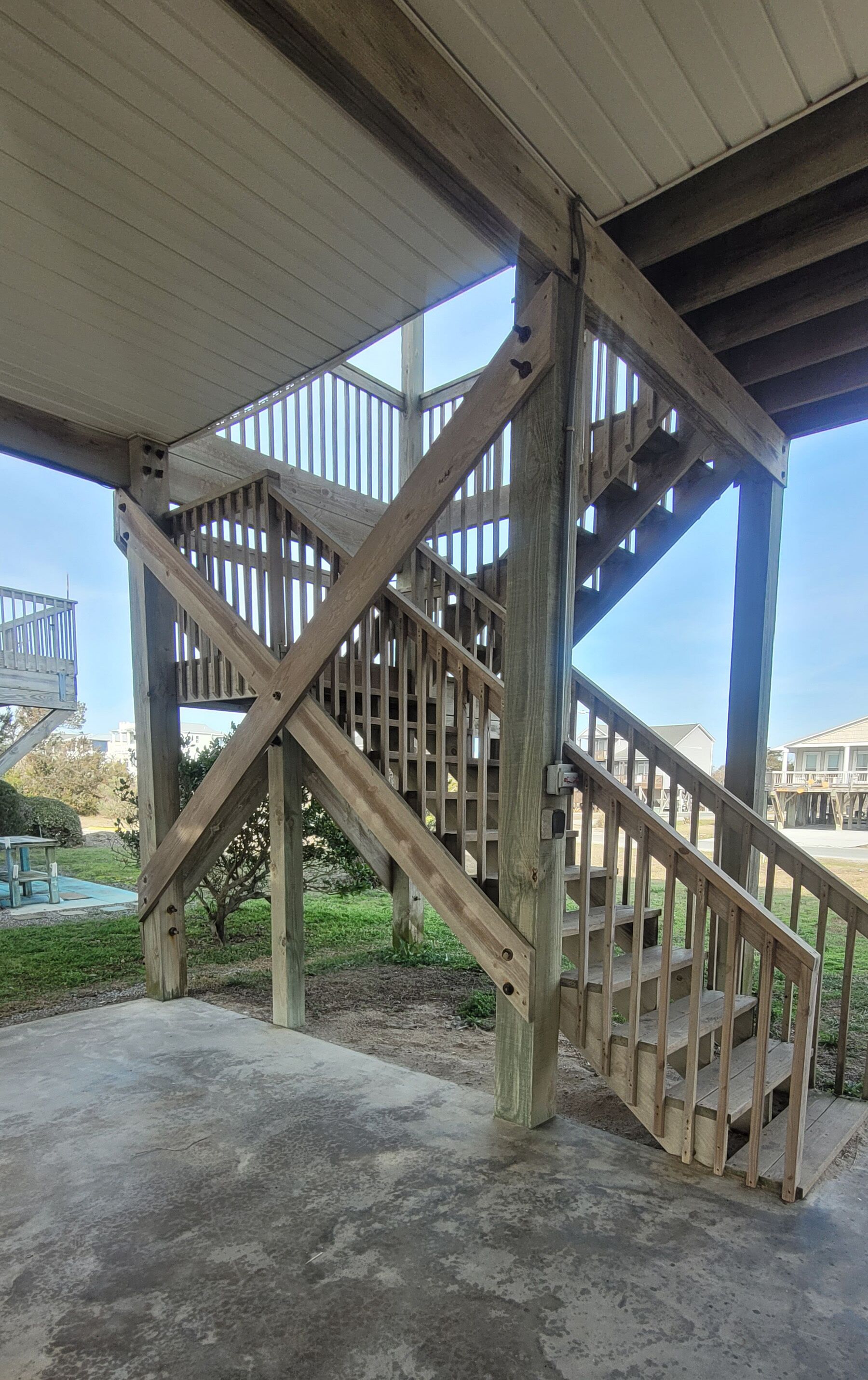 A wooden staircase with a metal railing leading to a covered area.