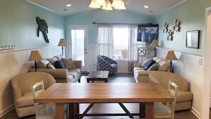 A living room with a wooden dining table, two sofas, and a television.