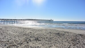 A beach with a pier extending into the ocean.