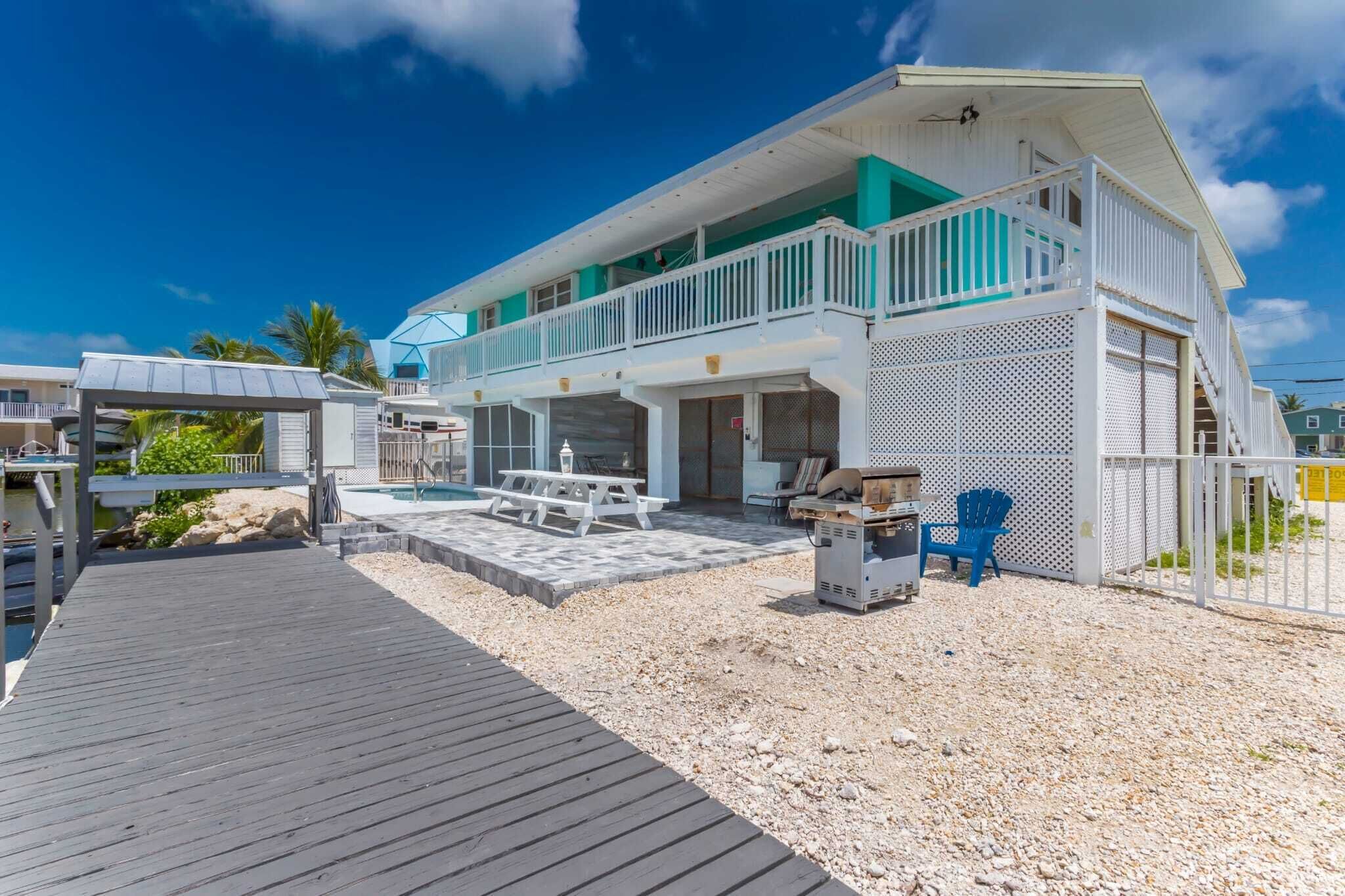 Ein zweistöckiges Haus mit überdachter Terrasse, Pool und Bootsanleger.