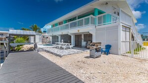A two-story house with a covered patio, a pool, and a dock.