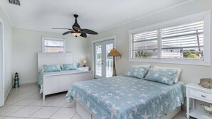 A bedroom with a bed, a nightstand, a ceiling fan, and a window with blinds.