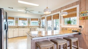 A modern kitchen with a large island, wooden bar stools, and a view of the outside. - Family Favorite 'Walker House' in Grayton Beach-Private Pool (Santa Rosa Beach)