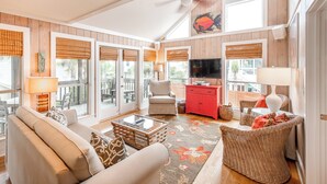 A spacious living room with a large window, a television, and a red cabinet. - Family Favorite 'Walker House' in Grayton Beach-Private Pool (Santa Rosa Beach)