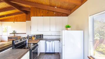 A modern kitchen with white cabinets, stainless steel appliances, and a wooden ceiling.