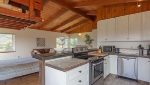 A modern kitchen with wooden beams, white cabinets, and stainless steel appliances. - Stunning Oceanview Coastal Home – Beach, Trails, Family Activities (Montara)