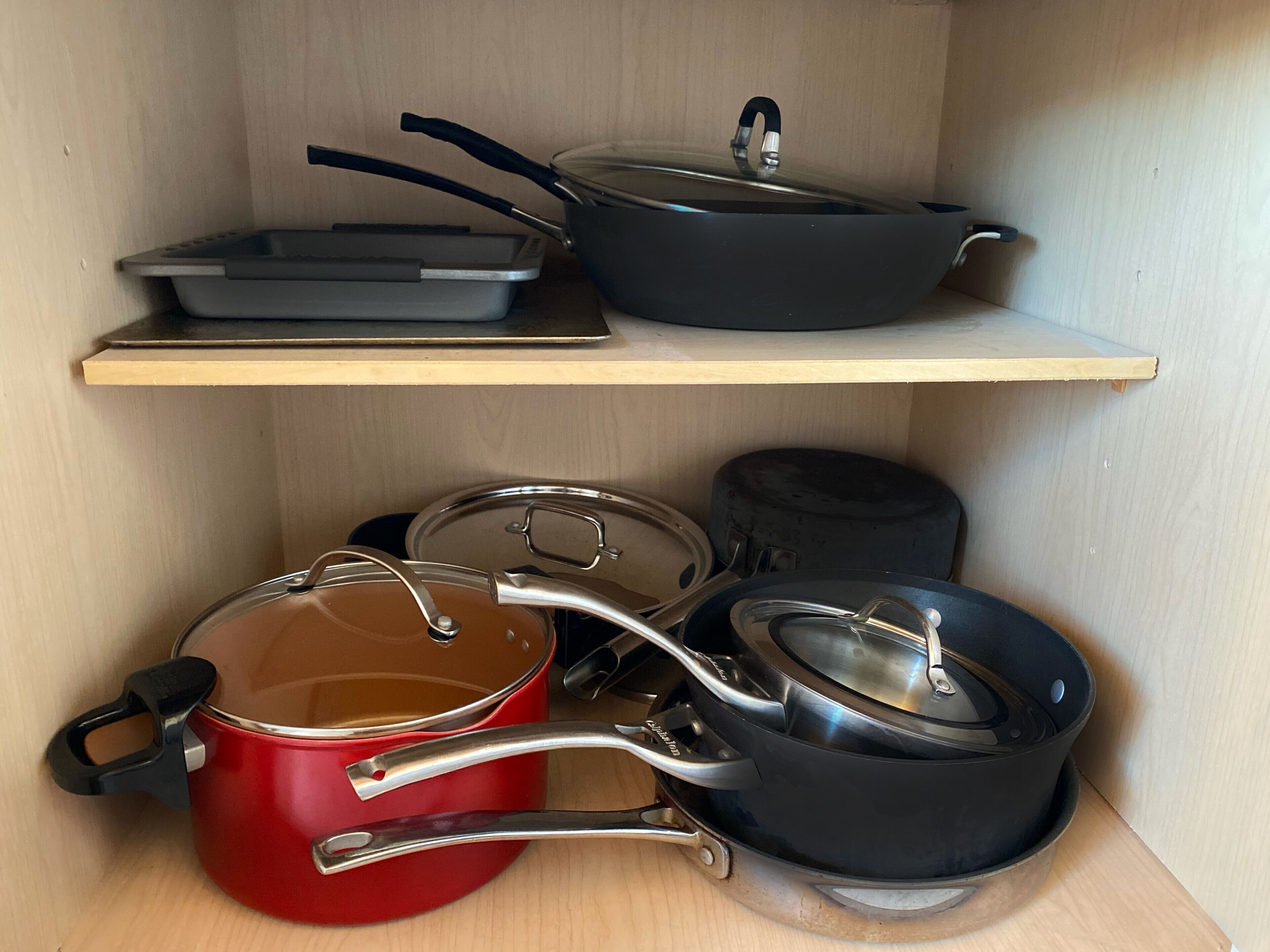 A kitchen shelf with various cookware including pots, pans, and a frying pan.
