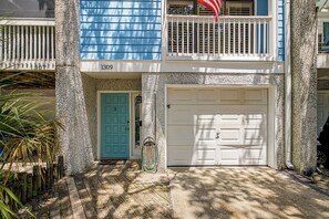 A two-story building with a blue exterior, a white garage door, and a turquoise door.