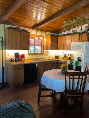 A kitchen with wooden cabinets, a dining table with chairs, a refrigerator, and hanging plants. - Magnificent View, In the woods! By Lodge & Golf course! Just Remodeled ceiling!  (Cloudcroft)