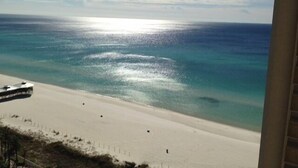 En strand med fri utsikt över havet och en byggnad i bakgrunden.