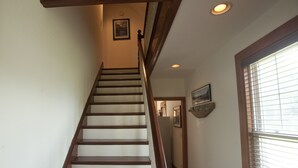Eine Holztreppe mit weißen Wänden und einem Fenster mit Jalousien.