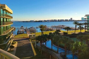 A waterfront hotel with a marina, a pool, and a city skyline in the background.