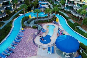 Um hotel com uma piscina ampla e sinuosa, espreguiçadeiras e uma área coberta.