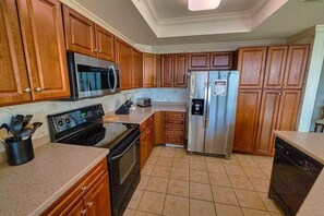 Uma cozinha com armários de madeira, geladeira de aço inoxidável, micro-ondas, forno e lava-louças.
