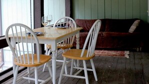 Un comedor con una mesa de madera y sillas blancas, un sofá rojo y una ventana con persianas.