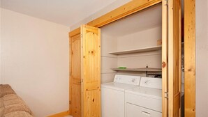 Ein Waschraum mit Waschmaschine und Trockner, Holzregalen und einer Holztür.