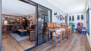 Amplia sala de estar con puerta corrediza de vidrio que da a una cocina, muebles de madera y un soporte para bicicletas.