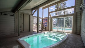 Un jacuzzi en un área exterior techada, con vistas a una piscina y un patio.