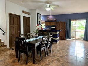 A dining area with a table and chairs, a kitchen with wooden cabinets, and a ceiling fan.