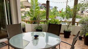 A glass-top table with four chairs, surrounded by potted plants on a balcony with a view of buildings. - Villa Papaya, 2 bedrooms, specious, comfortable home, beach walkable. (San Francisco)