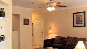 Una sala de estar con ventilador de techo, un sofá, una mesa de centro y una lámpara.