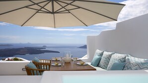 Un balcó amb taula per a dues persones, amb vista a un paisatge idíl·lic del mar i les illes.