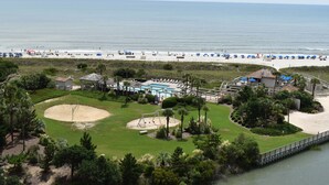 Un complejo turístico en la playa con piscina, sombrillas y un campo de golf.