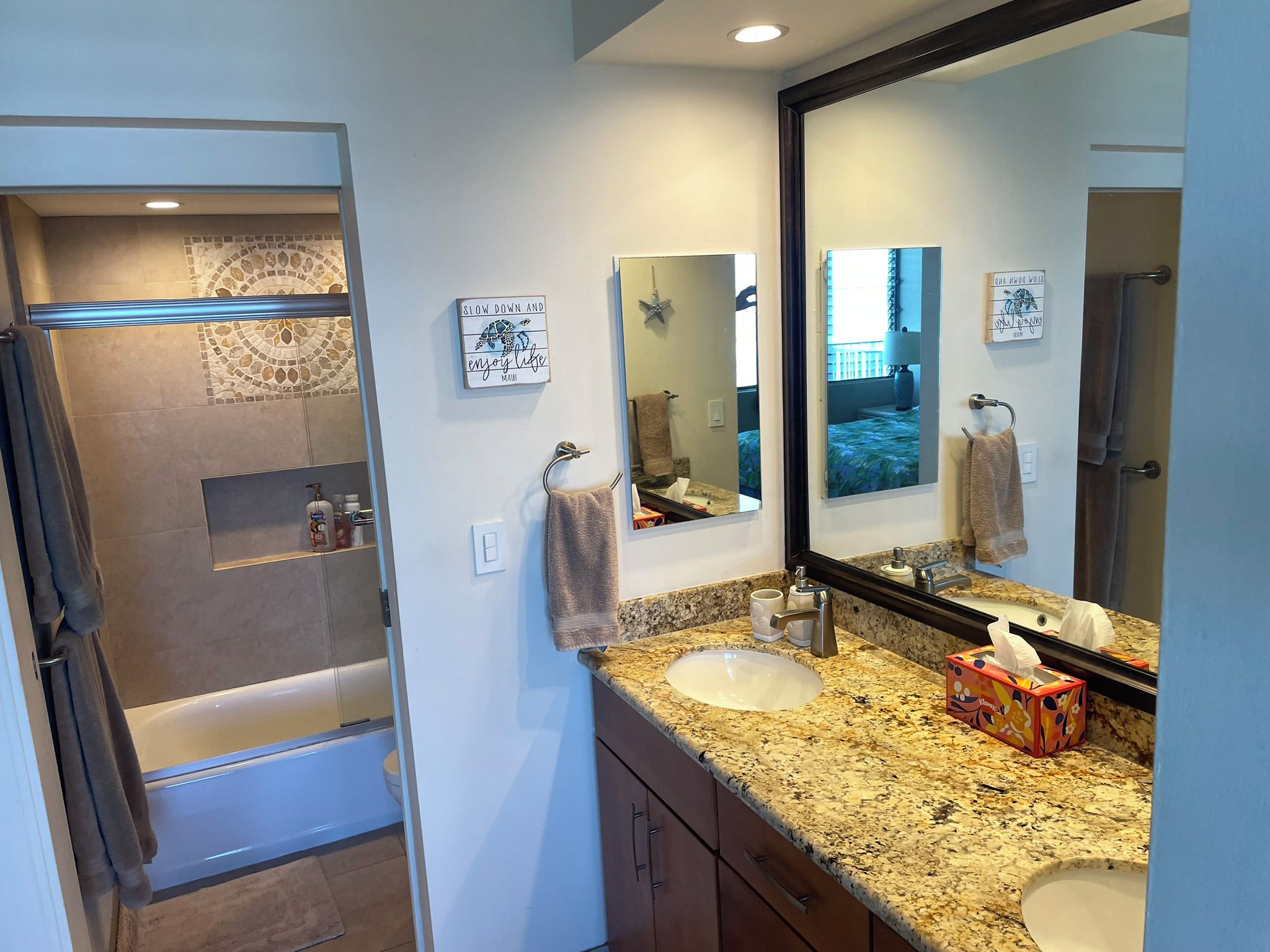 A bathroom with two sinks, a large mirror, and a shower area.