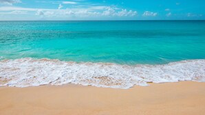 A beach with clear turquoise water and a sandy shore. - Villa Amaya - Modern, Pristine Villa, Stunning Ocean Views, Private Pool, Beach (Indigo Bay)