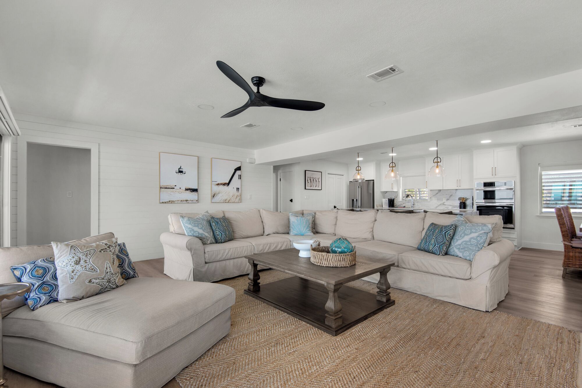 A modern living room with a sectional sofa, a coffee table, and a ceiling fan.