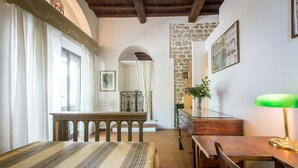 A room with a wooden table, a bench, a green lamp, and a stone wall. - Beautiful Villa, in Florence, shared pool, 12 guests, wifi, parking (Firenze)