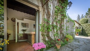 A rustic building with a wooden door, a tiled entrance, and a potted pink hydrangea. - Beautiful Villa, in Florence, shared pool, 12 guests, wifi, parking (Firenze)