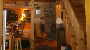 Un interior rústico con una escalera de madera, una zona de bar y un letrero que dice "THISTLE ROCK".