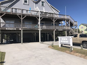A two-story building with a covered outdoor area labeled "WEST" and "EAST" for beach retreat guests.