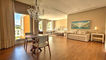 A spacious living room with a dining area, a chandelier, a sofa, and a painting on the wall.