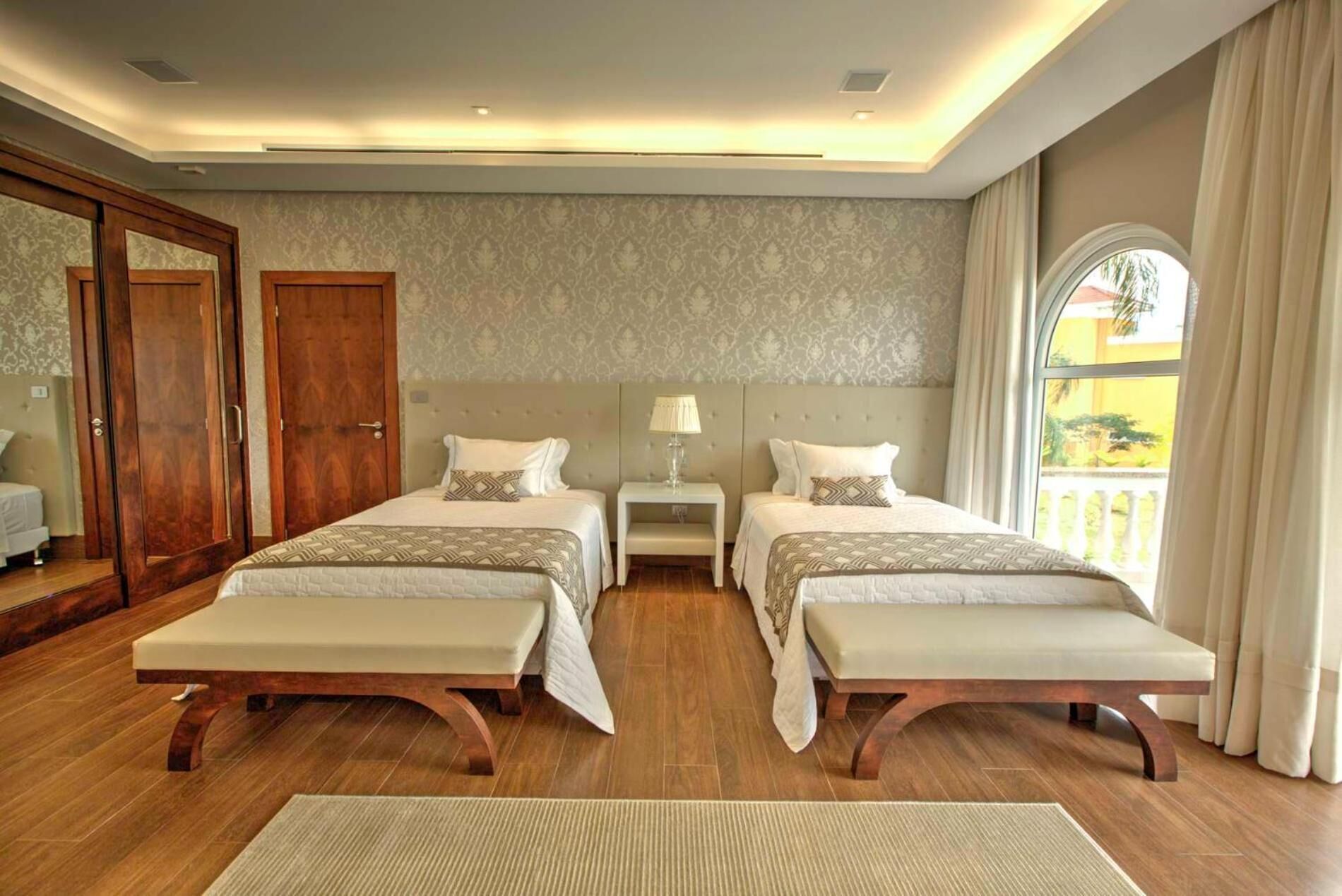 Une chambre d’hôtel avec deux lits, un grand miroir, une armoire et un balcon avec vue.