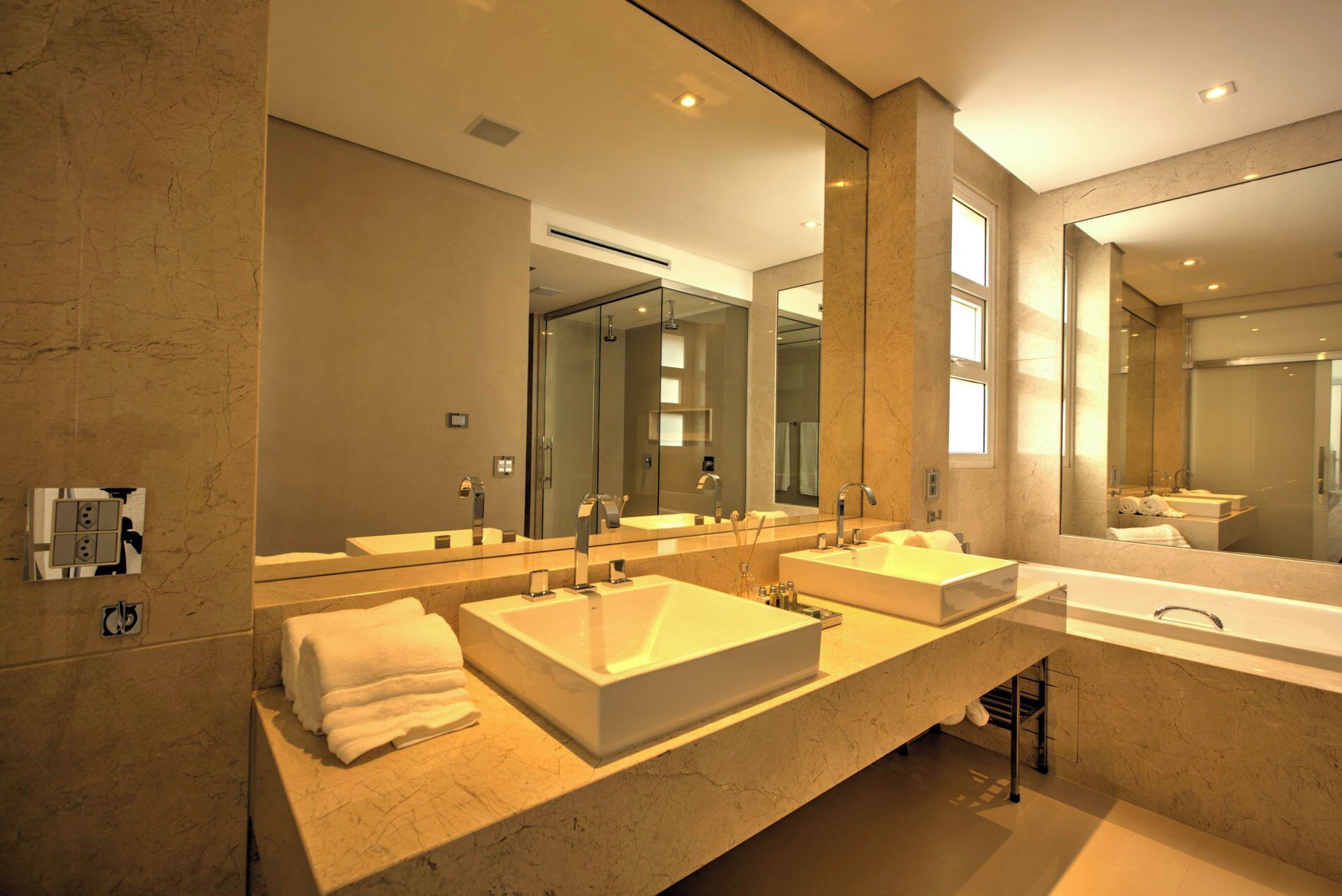 A modern bathroom with two large sinks, a bathtub, and a large mirror.