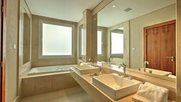 Une salle de bain moderne dotée d’une grande fenêtre, d’une porte en bois et d’un long meuble-lavabo avec deux vasques.