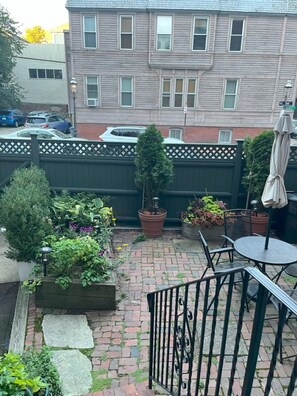 A patio area with a brick floor, a metal railing, and potted plants. - Historic Home At Freedom Trail (Boston)