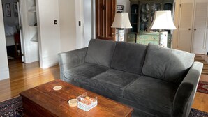 A living room with a grey sofa, wooden coffee table, and a cabinet with glass doors. - Historic Home At Freedom Trail (Boston)