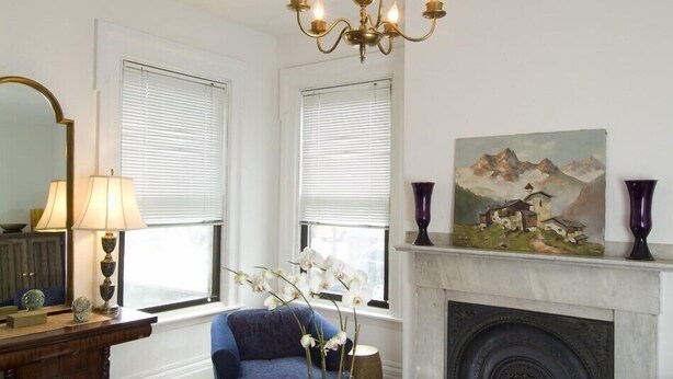 A living room with a fireplace, a chandelier, and a painting on the wall. - Historic Home At Freedom Trail (Boston)