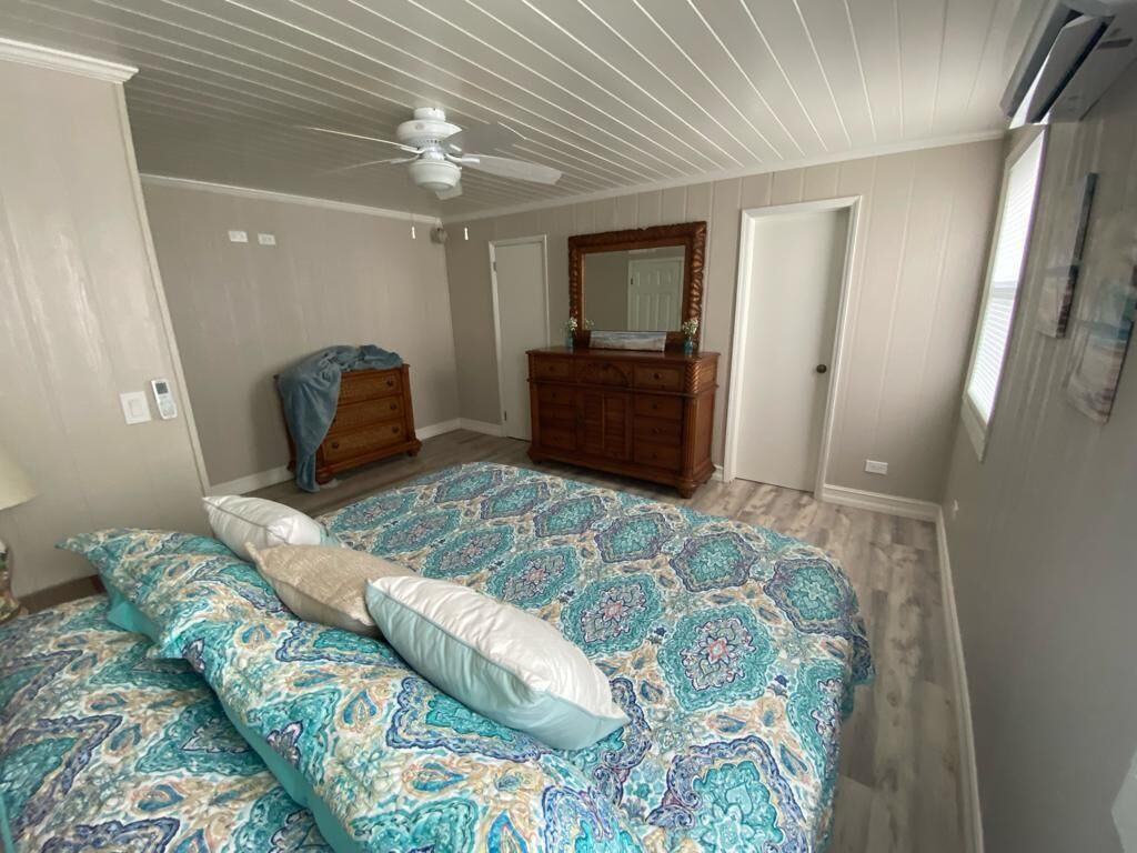 A bedroom with a bed, dresser, and ceiling fan.