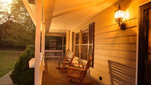 A wooden porch with rocking chairs and a wall-mounted light fixture. - Hendersonville Ranch Getaway that is just 30 minutes from Music City (Hendersonville)