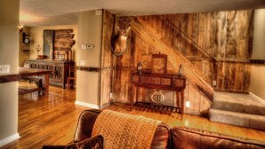 A rustic interior with wooden walls, a mounted deer head, a staircase, and a dining area with a wooden table and chairs. - Hendersonville Ranch Getaway that is just 30 minutes from Music City (Hendersonville)