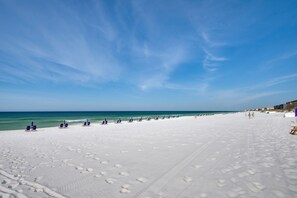 A beach with white sand and a clear blue sky.
