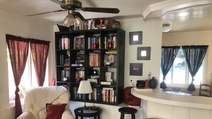 Una sala de estar con una estantería, un sofá, una mesa de centro y una zona de bar.