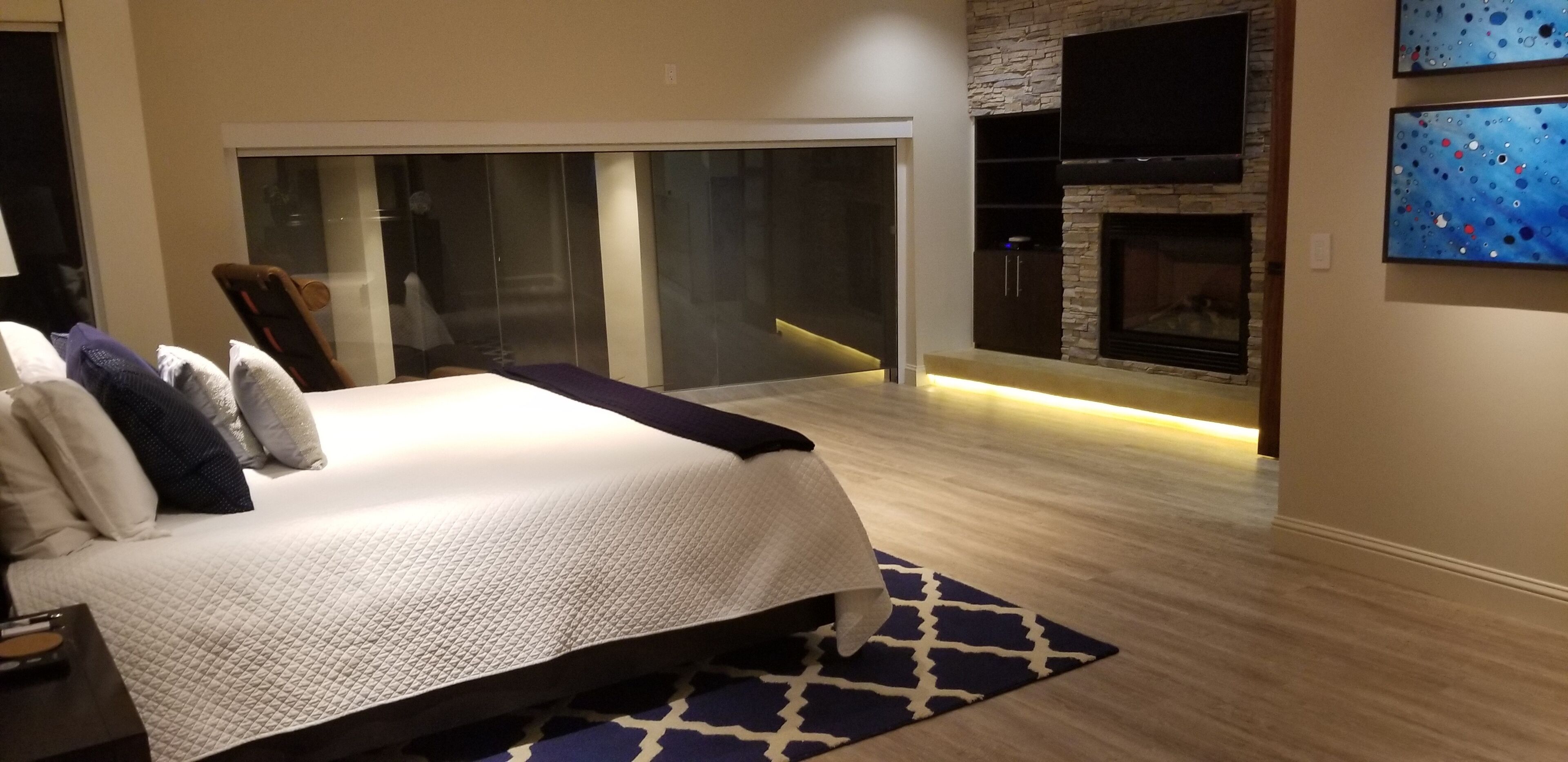Een moderne slaapkamer met een groot bed, een open haard en een glazen schuifdeur die leidt naar een balkon.